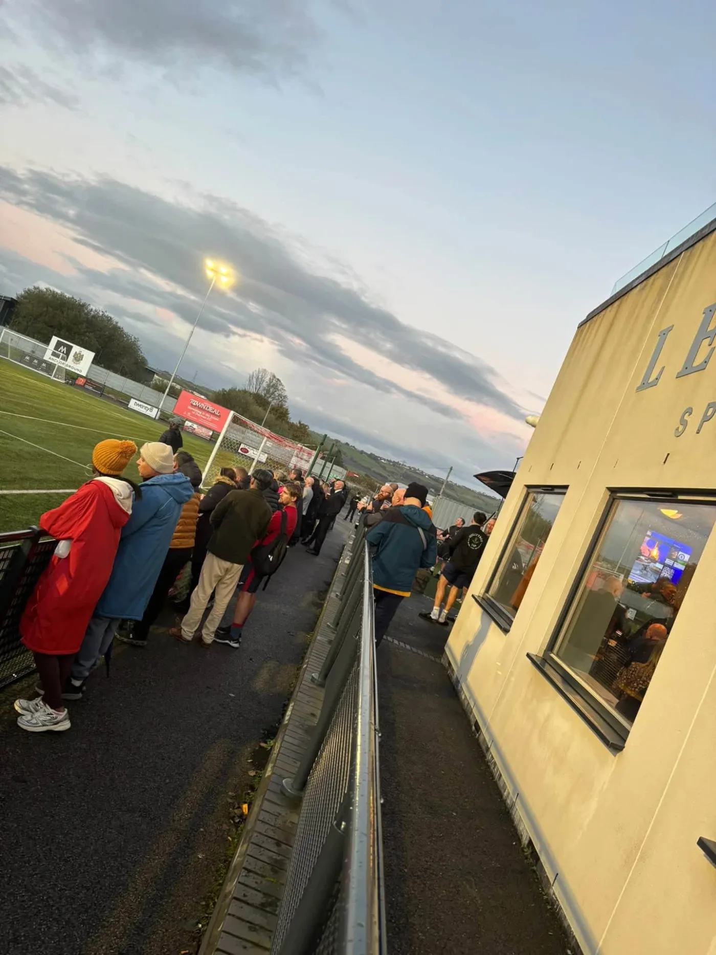 Supporters lining the pitch-side path by the Legends Sports Bar under the floodlights